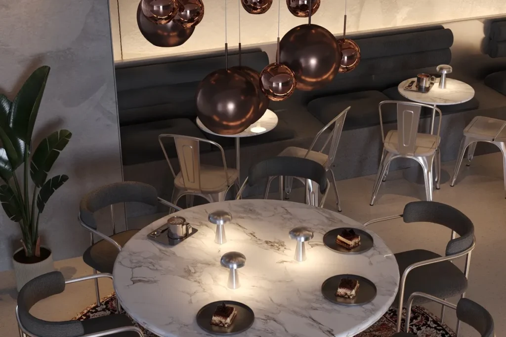 Cafe dekorasyonu, bakır sarkıt aydınlatmalar, mermer yuvarlak masa ve koyu renk banket oturma alanı