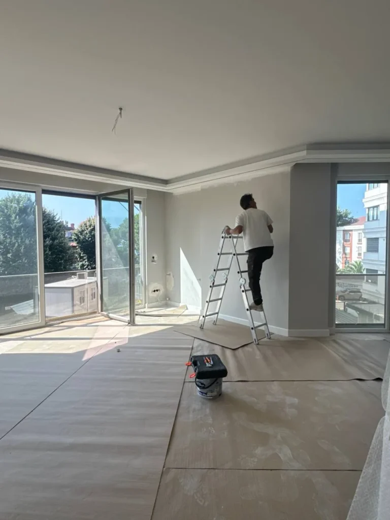Usta merdiven üzerinde salonun tavan ve duvar son işlerini yaparken