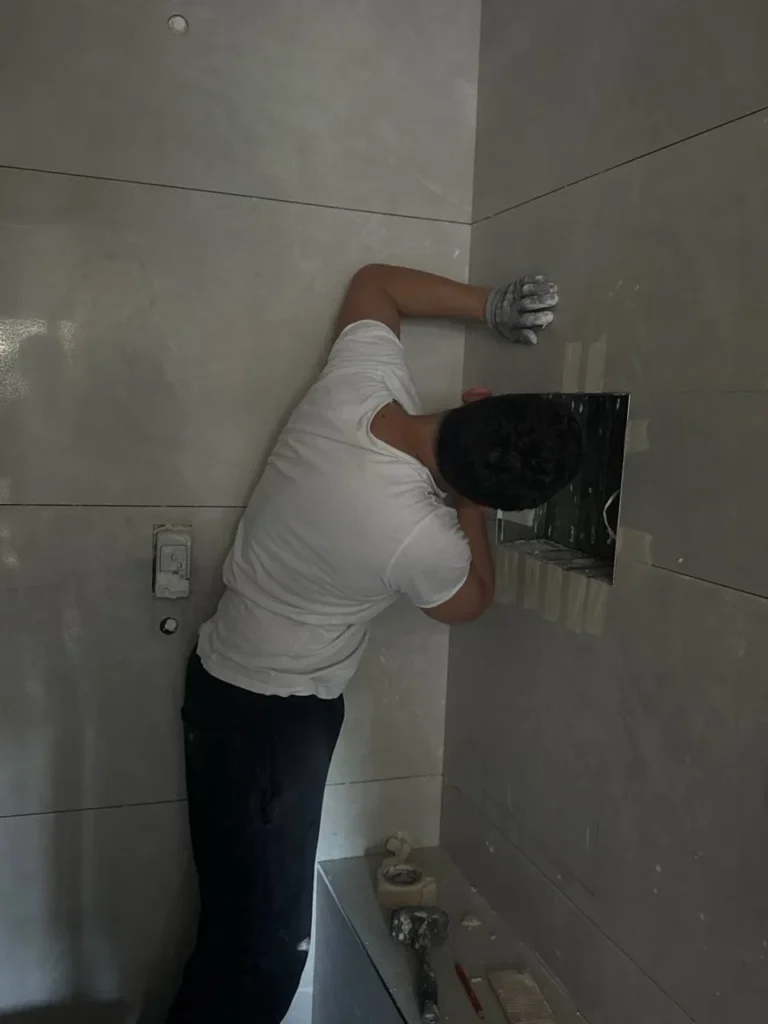 Usta banyo duvarına seramik döşerken